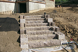 Ландшафтная лестница из искусственного камня, встроенная в склон, связывает дом террасируемым склоном